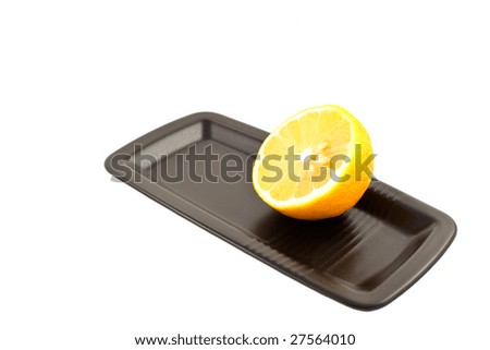 half of lemon on a black square plate on a white background