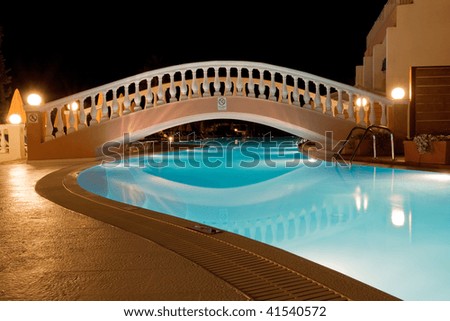 pool of Greek hotel with small bridge at night