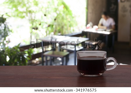 a cup of coffee on a blurry of  coffee shop background , someone working and relaxing in cafe