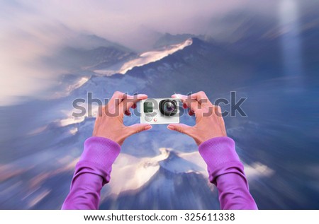 Action camera in skydiver hand. Nice illustration ready to your skydiving web site. Small cam holding in hands. Mountain jump background. Sport camera icon presentation.