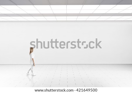 Empty big hall wall mockup. Woman walk in museum gallery with blank wall. White clear stand mock up lobby. Display artwork presentation. Art design empty floor. Expo studio wall in loft corridor.