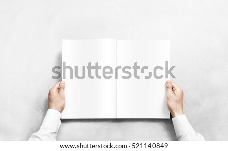 Hand opening white journal with blank pages mockup. Arm in shirt holding clear magazine template mock up.