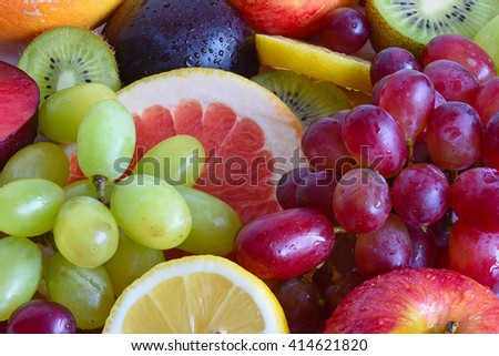 Grape, apple, kiwi and other fruits close-up. Fruit slices. Fruit set. Red fruits. Green fruits, yellow fruits. Fresh fruits. Drops of water on the fruit.