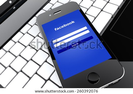 Tourin, Italy - March 14, 2015: Black Smart Phone with Facebook Social Network Screen on a laptop.