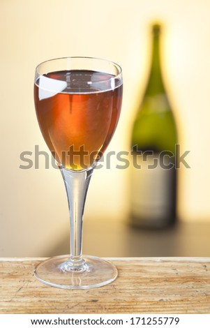 photo of glass of orange wine on wooden table and bottle on warm background.selected focus used