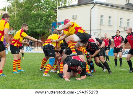 MOSCOW - MAY 13: S. Gernyan (12) jump on back of enemy on Russian Rugby Championship 2014 game Slava CSP (yellow) vs Metallurg (black), on May 13, 2014, in Moscow, Stadium Slava, Russia. Slava won 3:0
