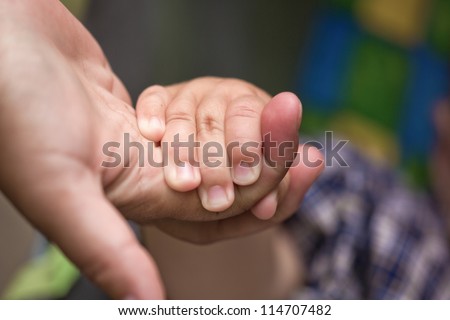 The hand of the child holds a hand of the adult