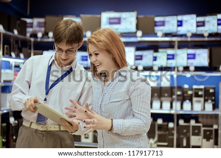 The seller-adviser shows the girl a new tablet computer