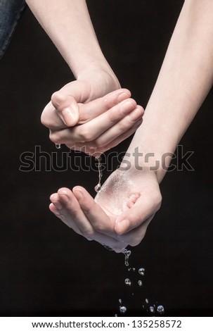 From hands drops of water fall