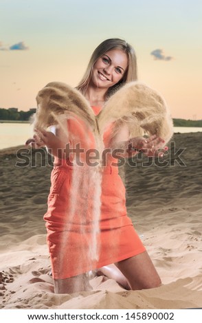 The young woman on a beach throws sand