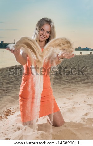 The young woman on a beach throws sand