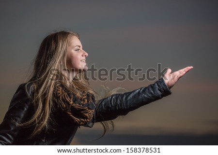 The girl pulls a hand on a background of the evening sky