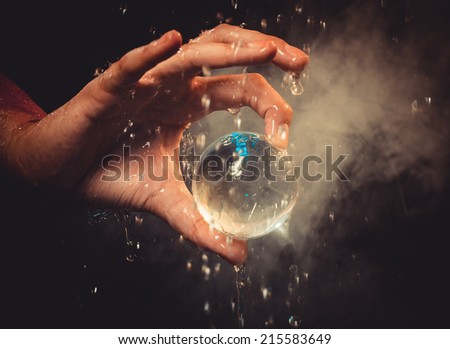 The hand holds a glass sphere