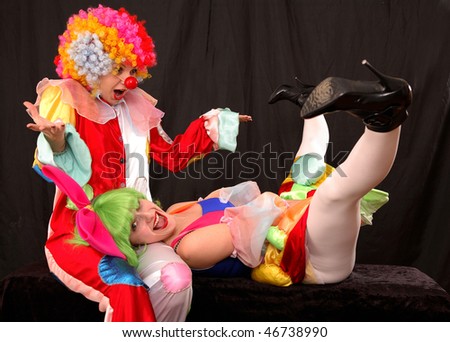 Two clown-girls in wigs and fancy costumes playing fools