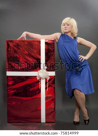 The girl in a dark blue dress costs on a black background with the big red box