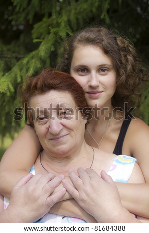 Young woman with her elderly mother against firtree