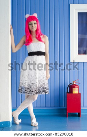 Young pretty girl with creative pink hair stands near the fire extinguisher