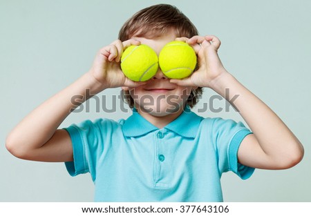 Little boy holding tennis balls instead of the eyes