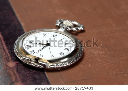 big old silver pocket watch with rusted antique book with leather back on the background