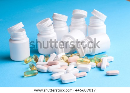 Many pills and tablets isolated on light blue background. Pharmaceutical medicament, cure in container for health. Antibiotic, painkiller closeup. Copy space for text.