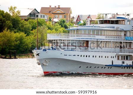 White river cruise boat with bank and houses on a background
