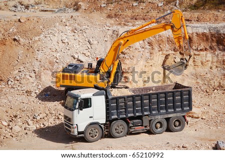 excavator loading dumper truck with sand at construction site