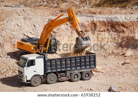 excavator loading dumper truck with sand at construction site