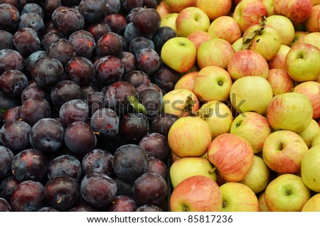 close up of apples and plums on market stand