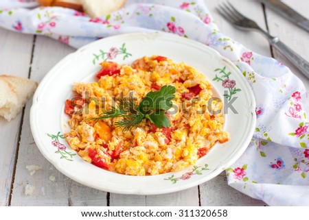 Scrambled eggs with tomatoes on a plate with bread