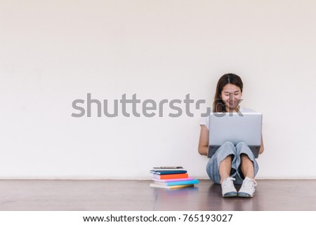 College student girl making report with laptop , sitting at school building. Outdoor education concept.