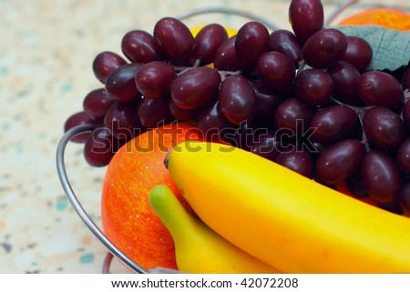 Plastic fruit - bananas, apples and grapes close-up