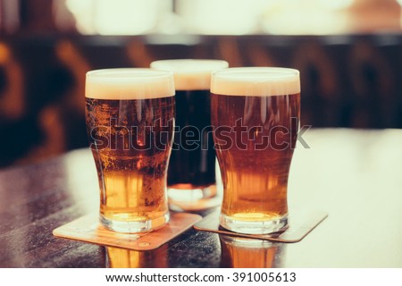 Glasses of light and dark beer on a pub background.