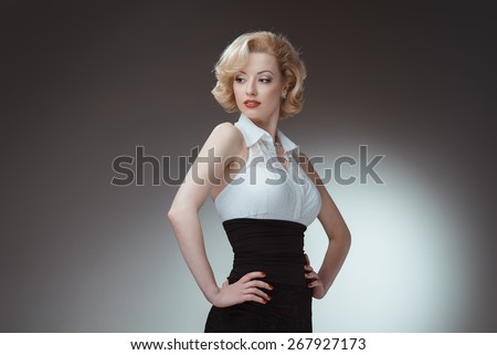 Pin-up girl, 50 style. Studio shot of young and beautiful woman wearing white blouse and black fitting, in studio. Professional makeup and hair style