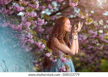 Beautiful pregnant woman smells blossom, outdoor in nature.