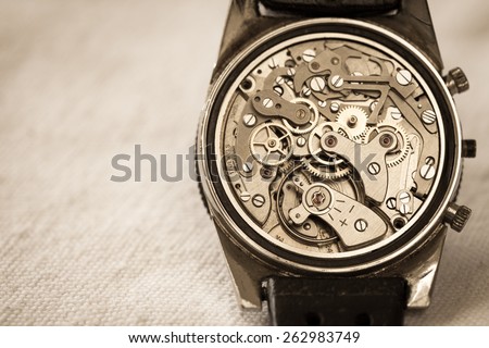 Vintage watch showing it\'s complex movement and parts. In sepia tone for mood.