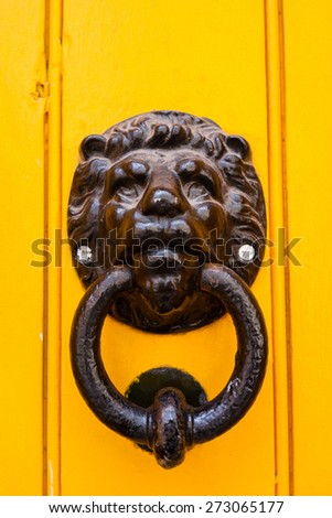 Cast iron lion door knocker on a yellow painted door, London.