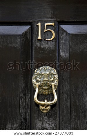 Lion design brass door knocker on a black painted door. London UK