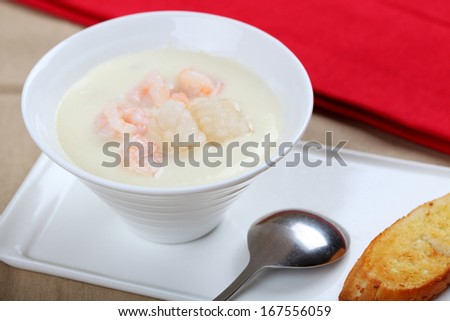 The bowl of seafood soup and bread in dish on the table.