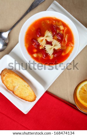 The bowl of  soup and bread in dish on the table.