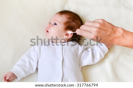 hand is cleaning baby\'s ear