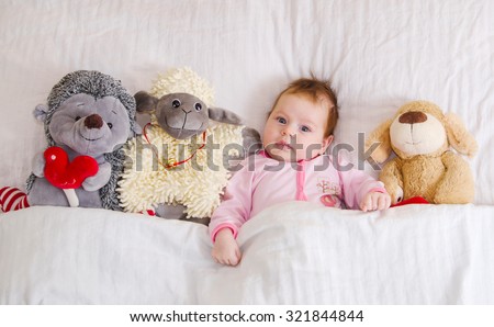 Sweet baby in bed with toys