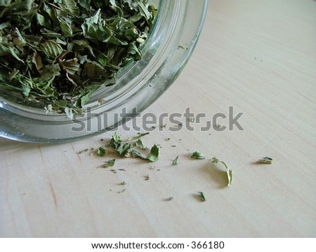 Green tea spilling out from a glass jar