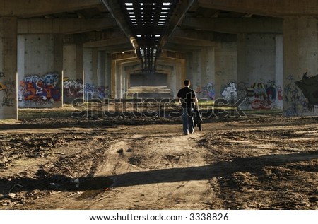 a person walking under anh old bridge, graffiti drawings all around him