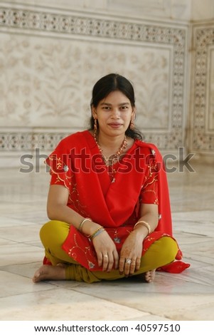 AGRA, INDIA - JUNE 17: Lovely Indian girl sitting by the Taj Mahal temple on June 17, 2007 in Agra, India. Local women wear saree (sari) as traditional clothing and often adorn their hands with henna