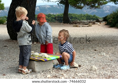 Tree boys play with stones as goods, play market outside