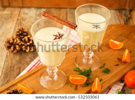 Christmas drink: eggnog with cinnamon and anise on wooden rustic background