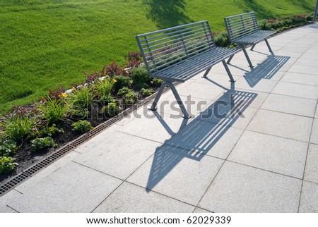 row of metal park benches with green grass behind