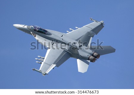Fighter jet loaded with missiles flying against a blue sky