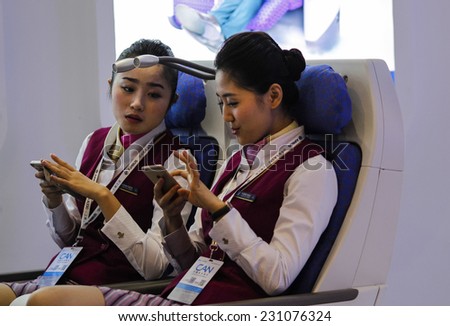 ZHUHAI, CHINA - NOV. 10. 2014:Flight attendants using their phones on the model seats on the stand of China Southern Airlines on Airshow China 2014 in Zhuhai, Guangdong province.