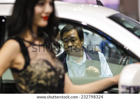 GUANGZHOU, CHINA - NOV. 21. 2014: Man looking in Cadillac Escalade car on the 12th China International Automobile Exhibition in Guangzhou, Guangdong province.